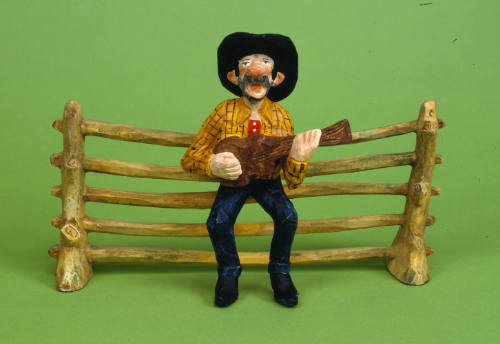 Cowboy Sitting on Fence Playing Guitar and Singing